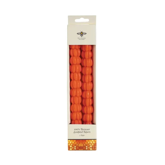 Big Dipper Wax Works 10-inch Sculpted Orange Pumpkin Tapers in retail packaging, front view against a white background, showing two orange beeswax taper candles with a stacked pumpkin silhouette shape inside a white windowed box labeled 100% Beeswax Sculpted Tapers, 1 Pair, with a Big Dipper Wax Works logo at the top and a honeycomb pattern at the base
